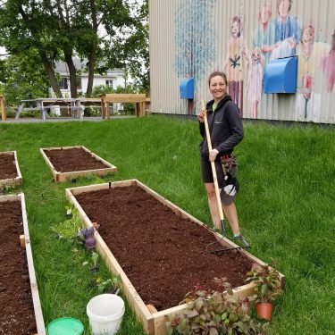 Une horticultrice sourit en passant le râteau dans un jardinet.