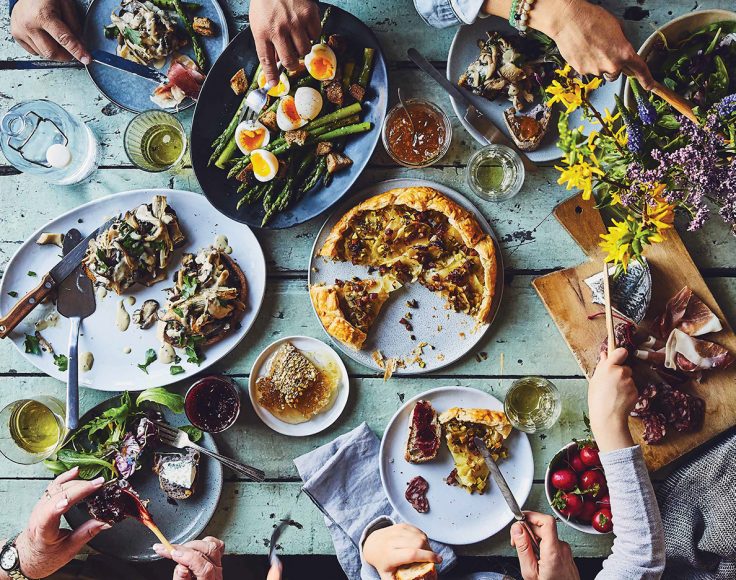 Couverture d'un magazine Caribou, où on voit de haut une table pleine de nourriture et les bras des personnes assises autour de la table.